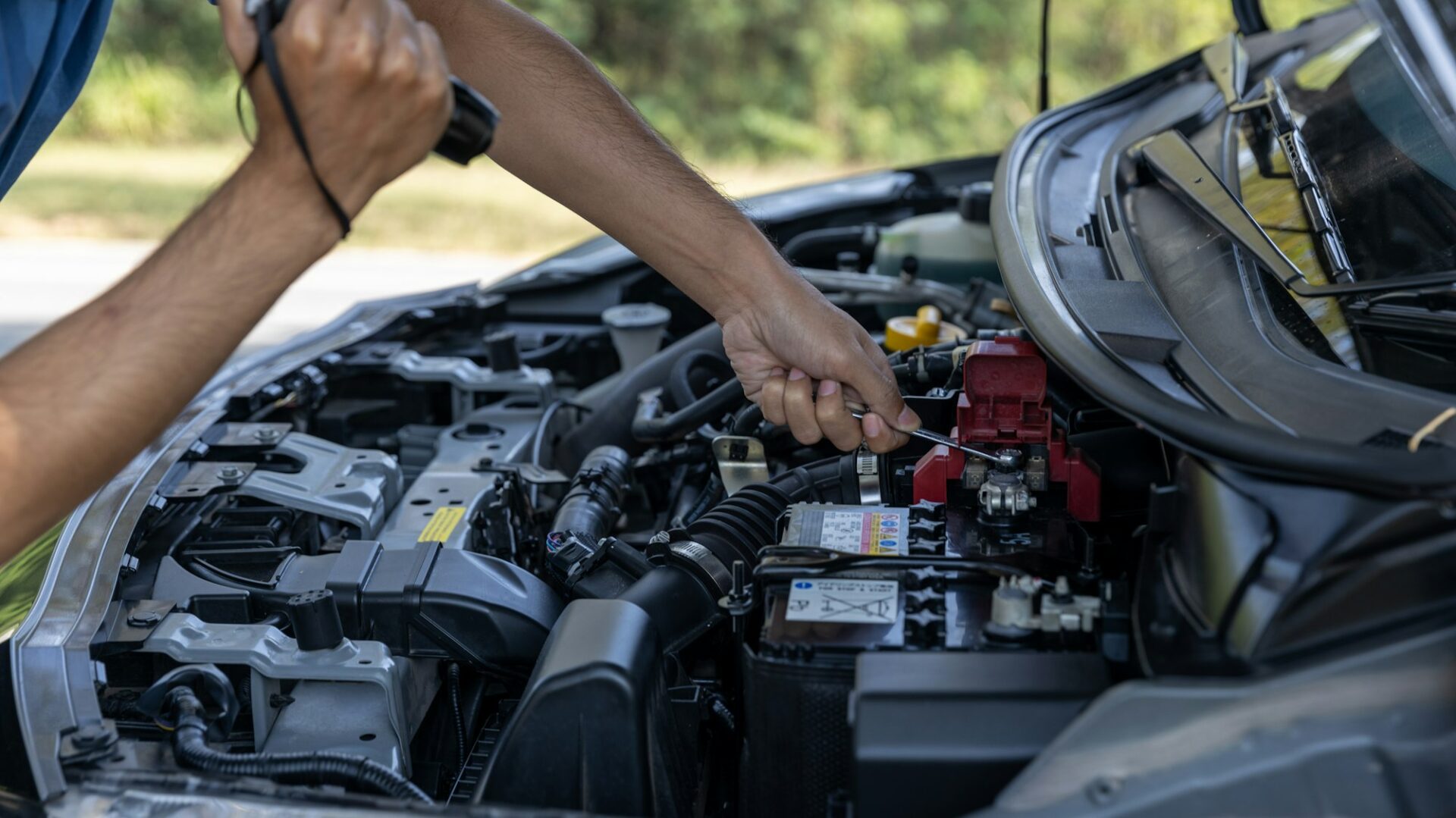L'homme vérifie la batterie de la voiture parce que la batterie de la voiture est épuisée. 