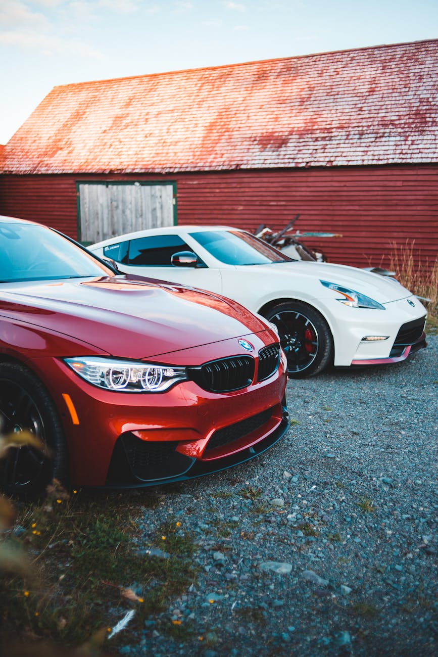 Nouvelles voitures de coupé rouges et blancs modernes garées sur un terrain pierreux près de la maison abandonnée Shabby à la campagne