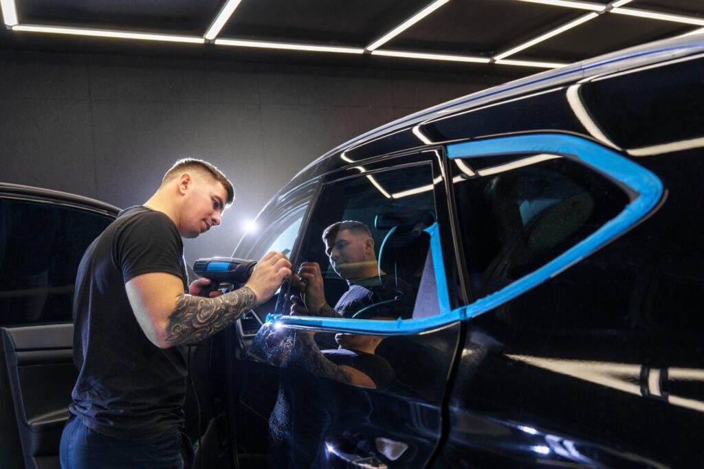 Autocollant d'un film de protection sur le phare d'une voiture dans un studio de détail de voiture. 
