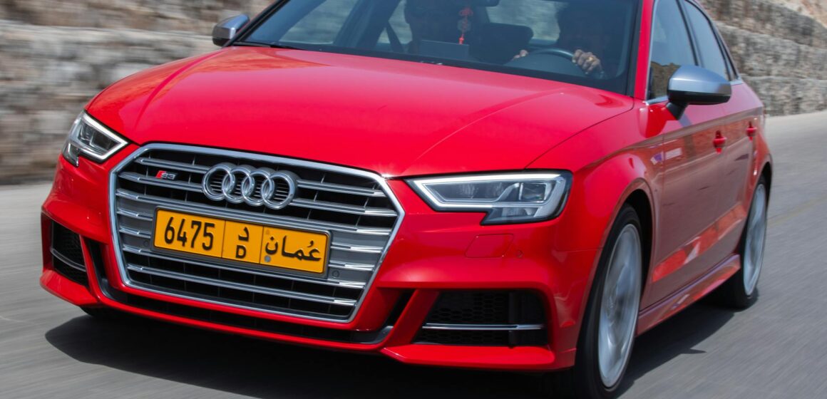 Audi-s3-8l-1999 Voiture rouge dynamique sur une route panoramique à Muscat, Oman, présentant le design et la vitesse modernes.