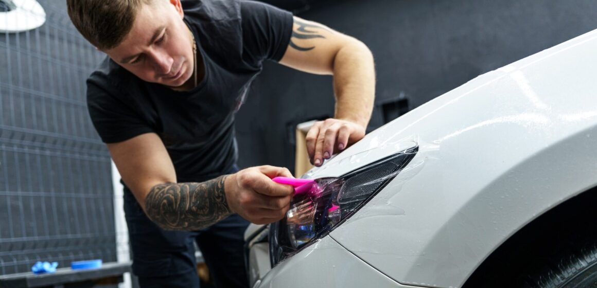car-customization Autocollant d'un film de protection sur le phare d'une voiture dans un studio de détail de voiture.