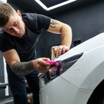 Autocollant d'un film de protection sur le phare d'une voiture dans un studio de détail de voiture. 