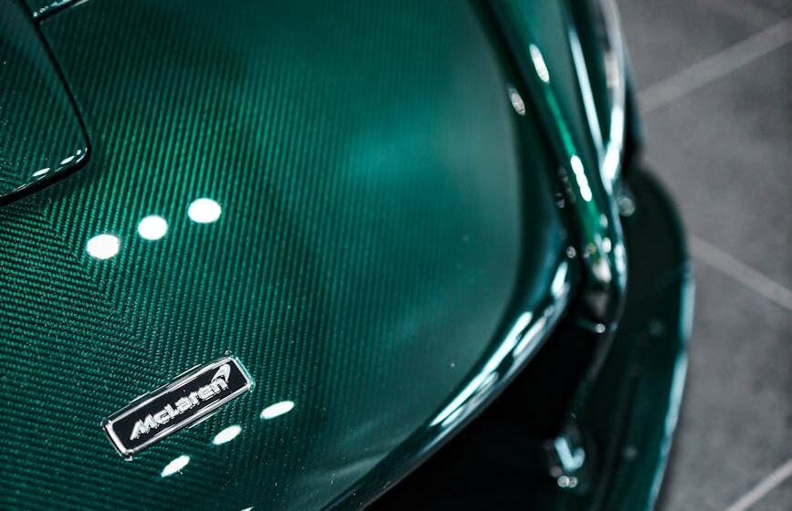 carbon-hood Hotte de supercar vert foncé avec texture en fibre de carbone dans une salle d'exposition.