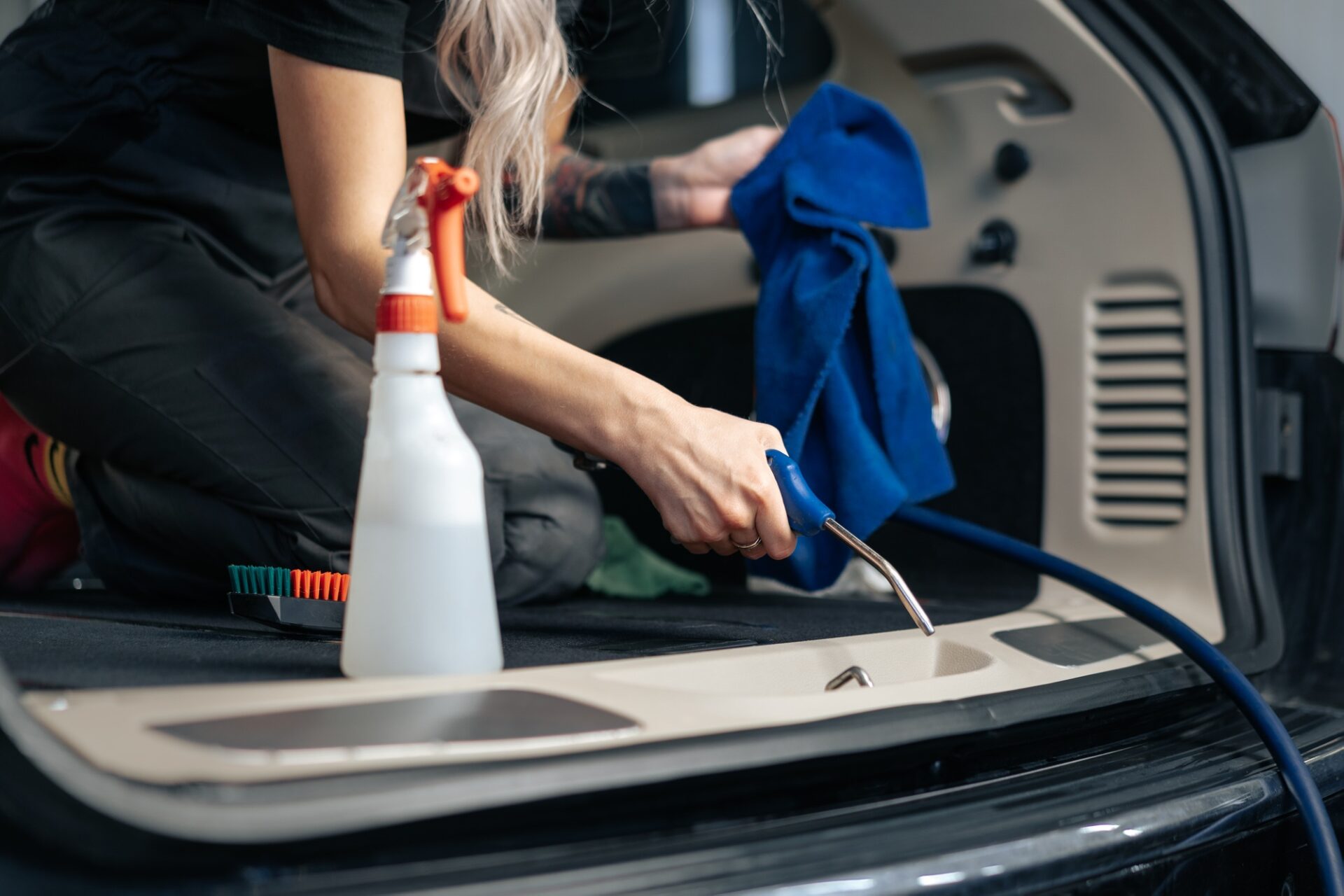 Salon de voiture de nettoyage des femmes avec pulvérisation de polissage dans le service de détail de la voiture, gros plan