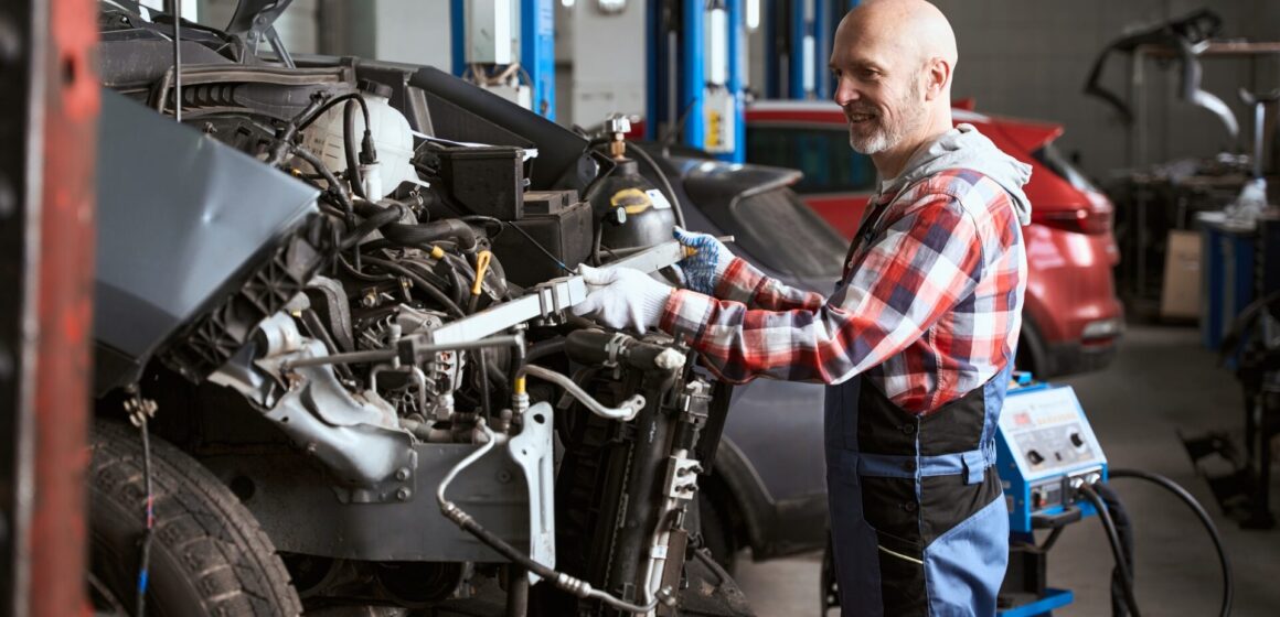 dismantle-car L'homme d'âge moyen se tient devant une voiture démantelée, le maître fait des mesures géométriques