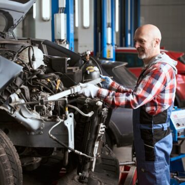 L'homme d'âge moyen se tient devant une voiture démantelée, le maître fait des mesures géométriques