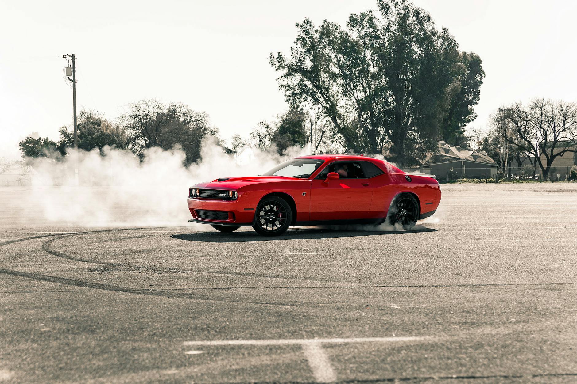 Une voiture de muscle rouge vibrante effectuant une dérive, créant de la fumée sur une zone d'asphalte ouverte à Sacramento, en Californie.