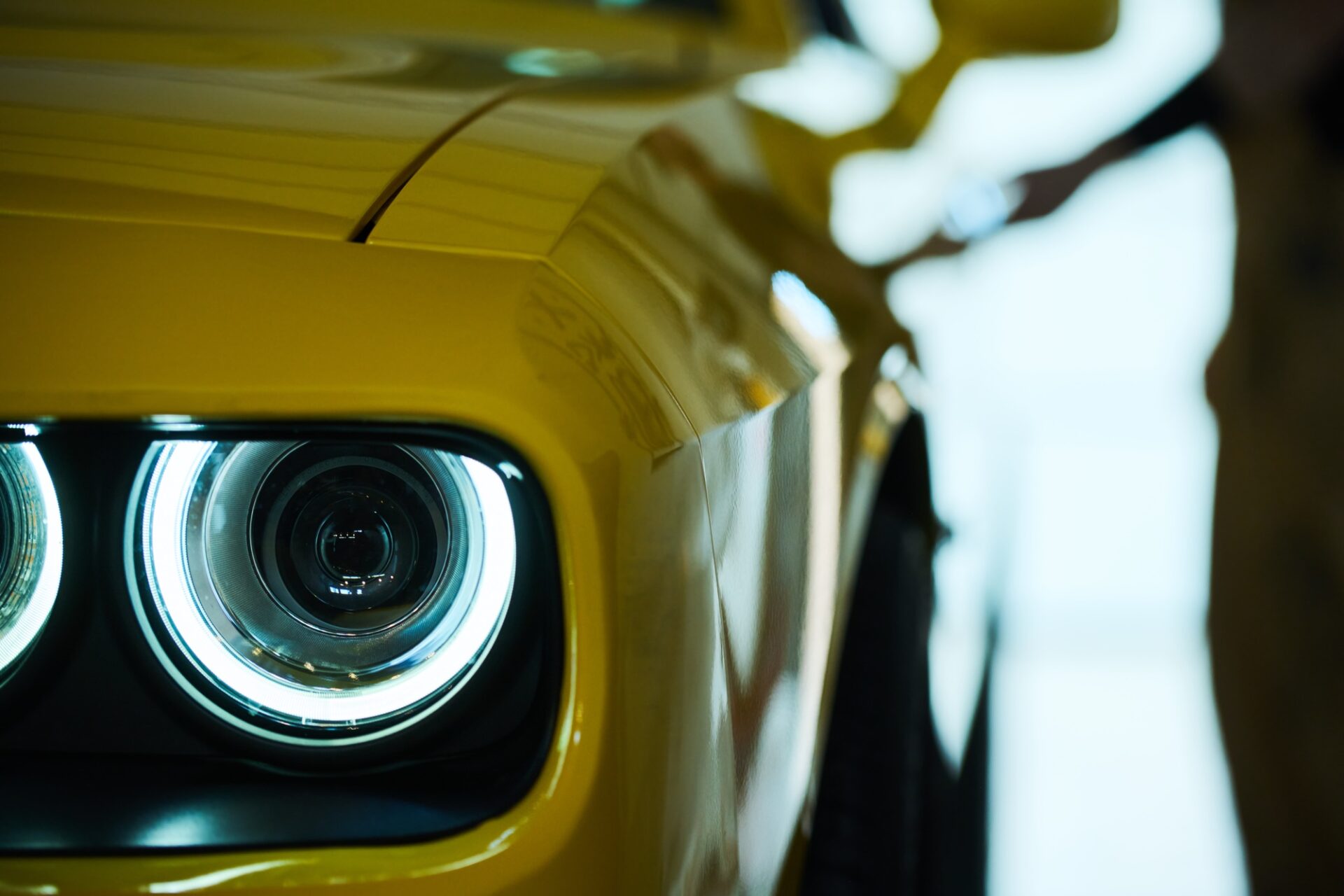 Phare sur la partie avant de la luxueuse voiture électrique de couleur jaune debout sur le site de parking, le garage ou l'atelier après réparation