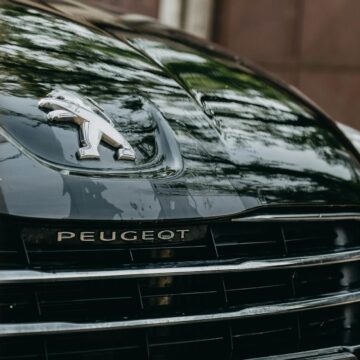 Disponible détaillé d'un capot de voiture Peugeot mettant en vedette le logo brillant et la calandre noire.