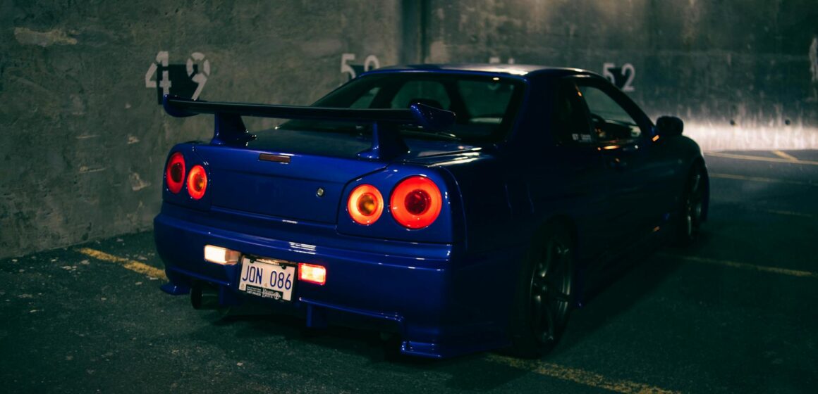 spoiler-wing Une voiture de sport bleu élégante avec un spoiler vu dans un parking nocturne.