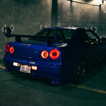 Une voiture de sport bleu élégante avec un spoiler vu dans un parking nocturne.