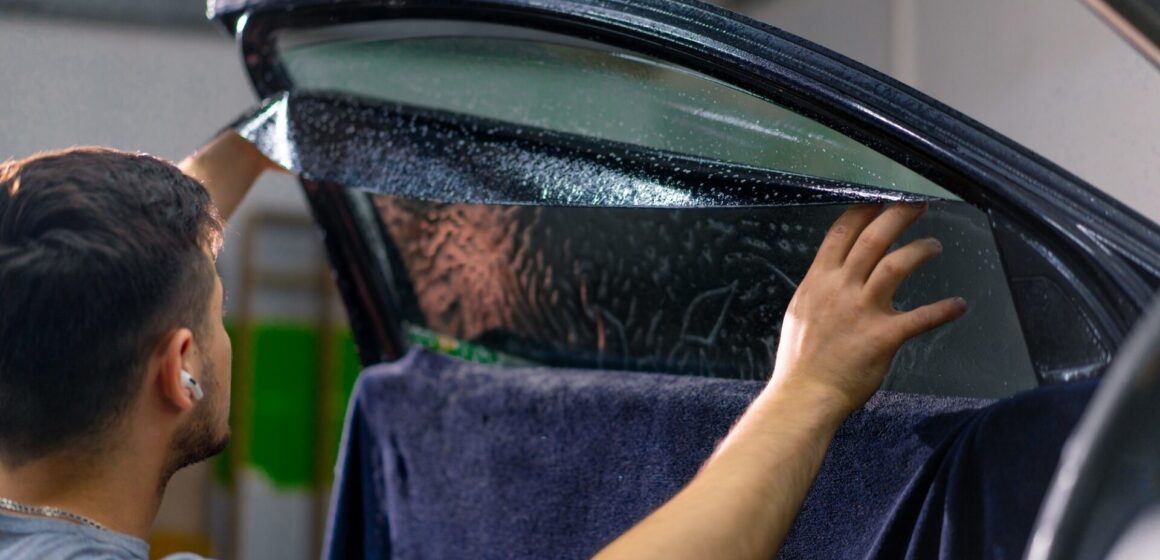 tinted-window Travailleur de service de voiture masculin à colle de fenêtre dans une voiture de luxe détaillant la voiture Réparer le concept de l'amour pour les voitures et la protection