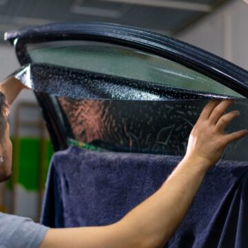 Travailleur de service de voiture masculin à colle de fenêtre dans une voiture de luxe détaillant la voiture Réparer le concept de l'amour pour les voitures et la protection