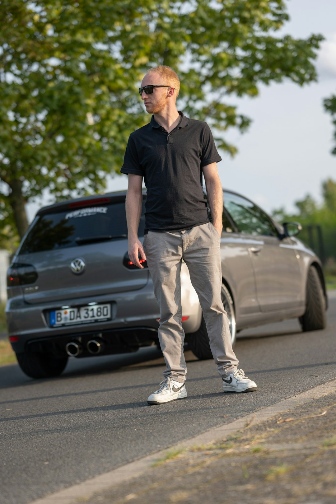 Un homme debout sur le bord d'une route à côté d'une voiture