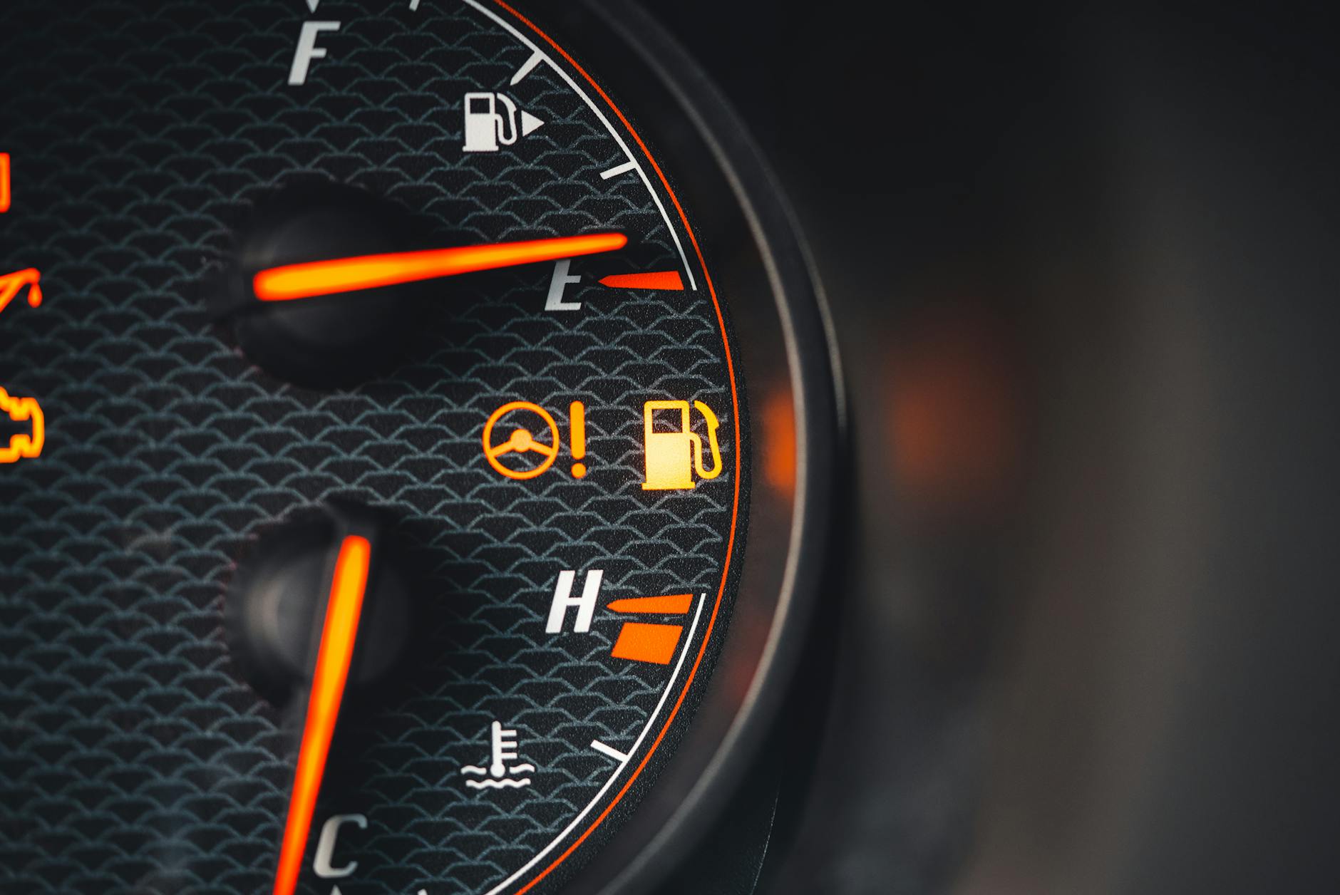 Vue détaillée d'un tableau de bord de voiture montrant des indicateurs de carburant et de température avec des pictogrammes brillants.