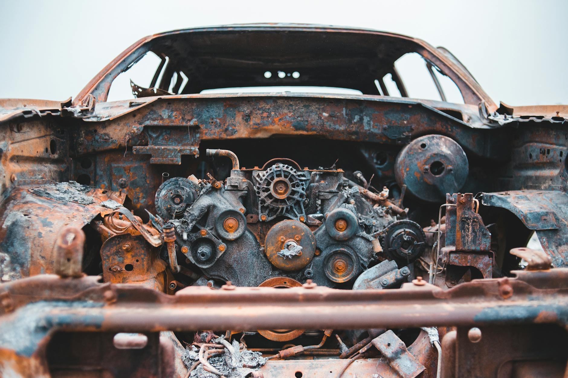 Tiche détaillée d'un moteur de voiture rouillé et abandonné, présentant la désintégration et la négligence.