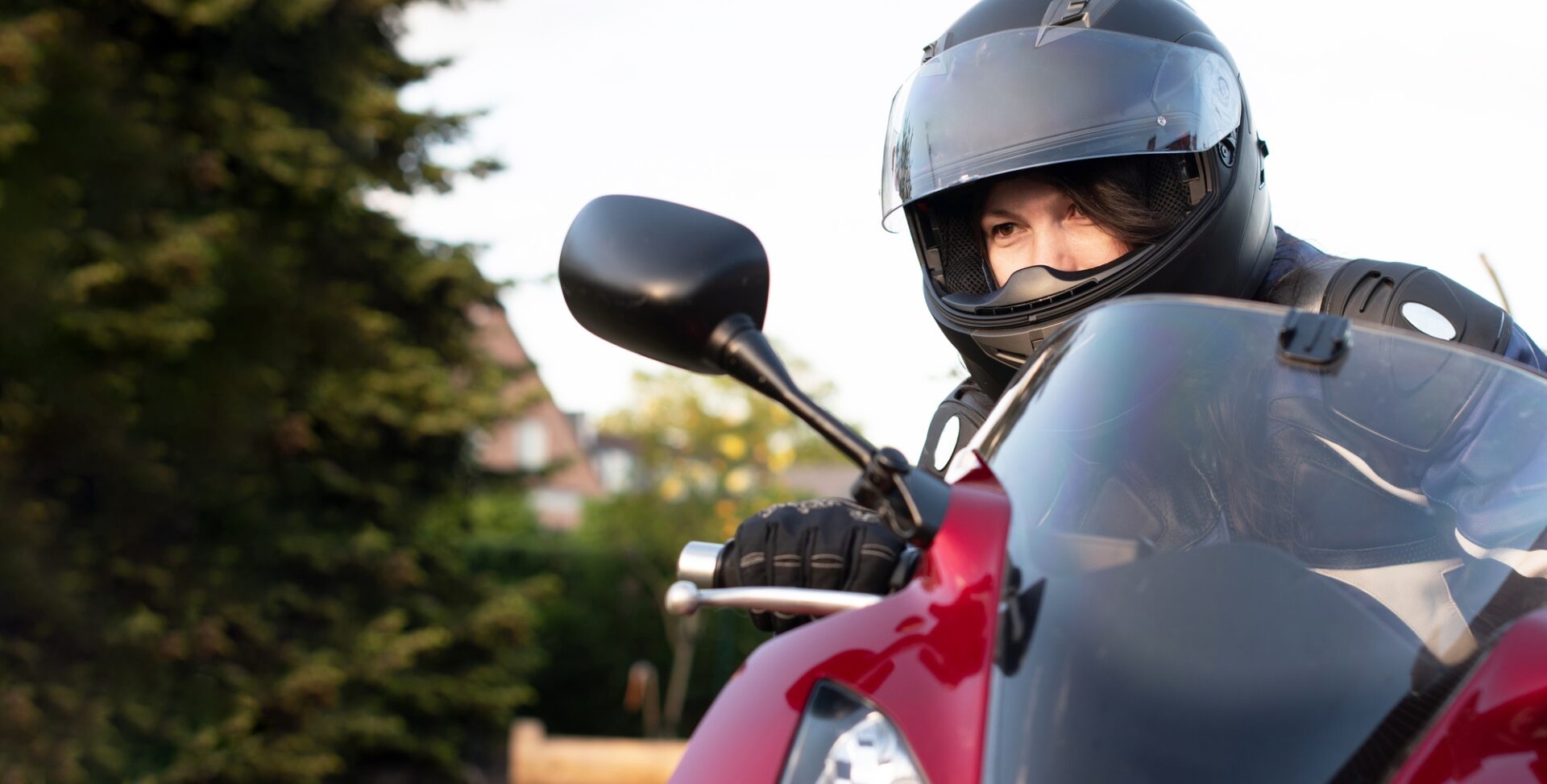 Une jeune fille motard dans un casque et un costume de moto conduisant une moto rouge en voyage, photo de haute qualité