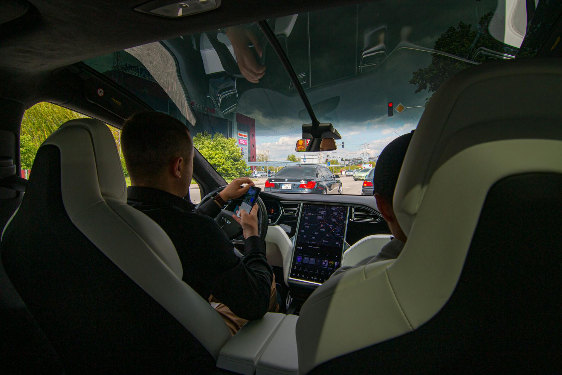 À l’intérieur d’un véhicule Tesla dans la circulation urbaine, mettant en valeur la technologie moderne et la conduite urbaine.