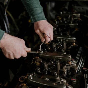 Gros plan d'un mécanicien utilisant des outils manuels pour réparer un moteur, faisant preuve de précision et d'habileté.