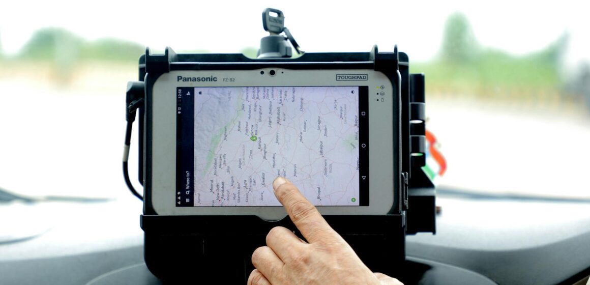 tracker-GPS Gros plan d'une main interagissant avec la navigation GPS sur un écran de tablette monté sur voiture, mettant en valeur la technologie moderne.