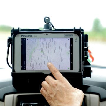 tracker-GPS Gros plan d'une main interagissant avec la navigation GPS sur un écran de tablette monté sur voiture, mettant en valeur la technologie moderne.