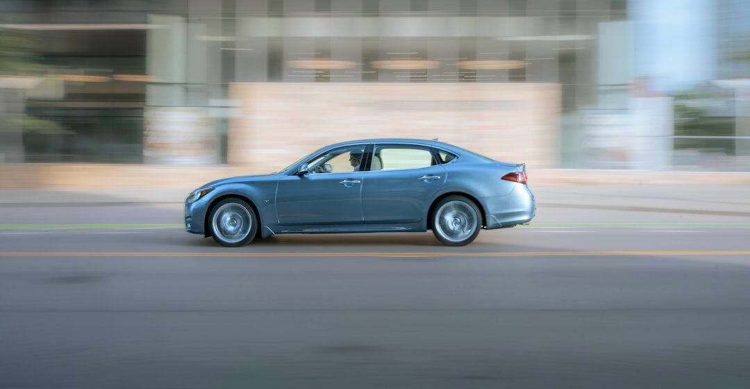 SLOW-CAR une voiture bleue circulant dans une rue à côté d'un grand immeuble