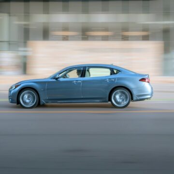 une voiture bleue circulant dans une rue à côté d'un grand immeuble