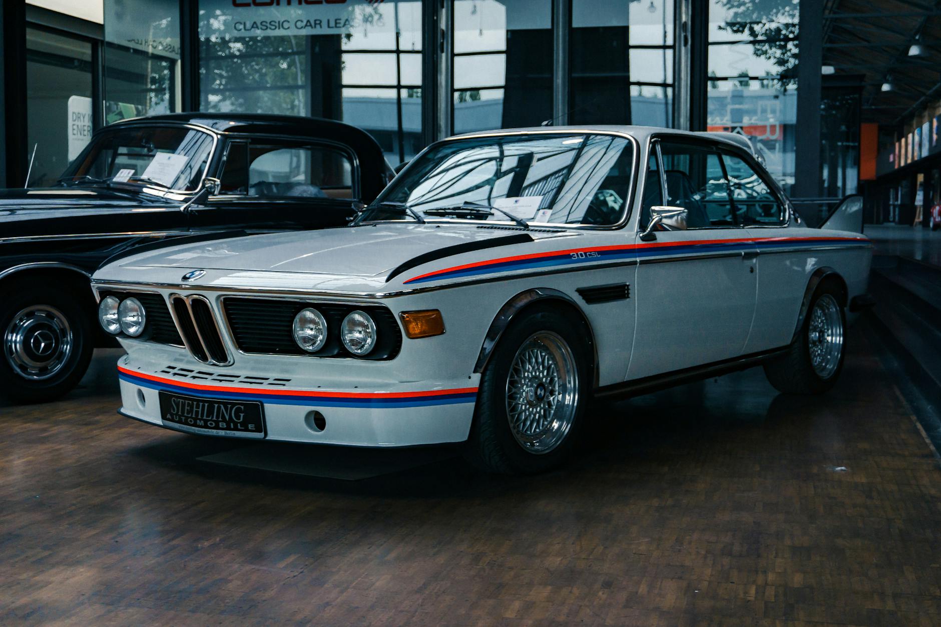 Présentation de voitures anciennes dans une exposition intérieure mettant l'accent sur le design classique et l'histoire de l'automobile.