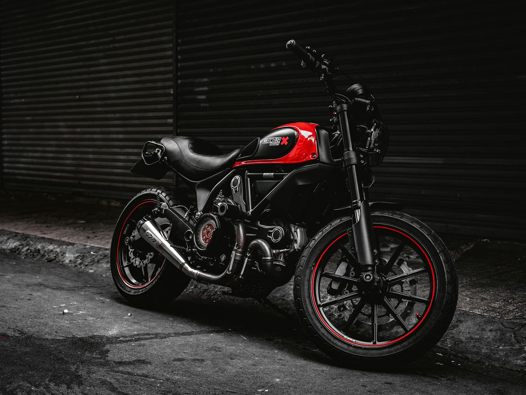 Photo d'humeur maussade d'une moto Ducati rouge garée dans une rue, respirant le style et la force.