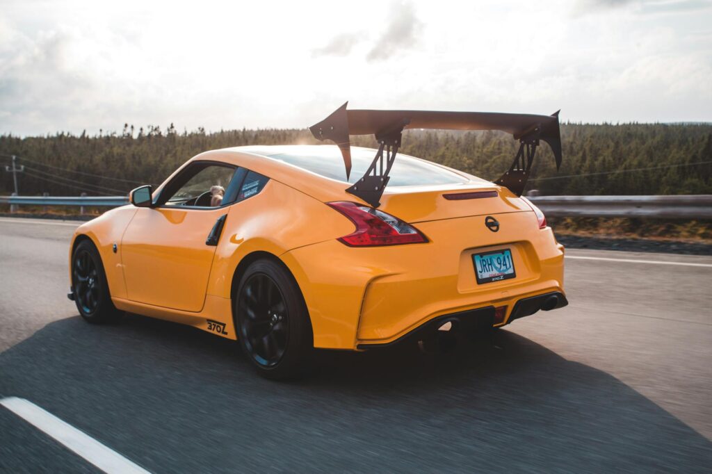 Une photo dynamique d'une voiture de sport jaune roulant à toute vitesse sur une autoroute avec en toile de fond une forêt pittoresque.