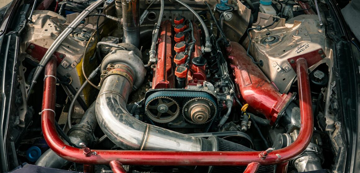 Coude-en-aluminium-voiture Vue détaillée d'un moteur de voiture modifié avec des accents rouges, mettant en valeur ses composants.