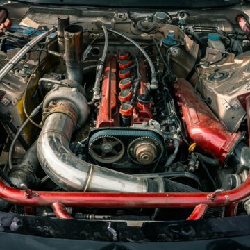 Coude-en-aluminium-voiture Vue détaillée d'un moteur de voiture modifié avec des accents rouges, mettant en valeur ses composants.