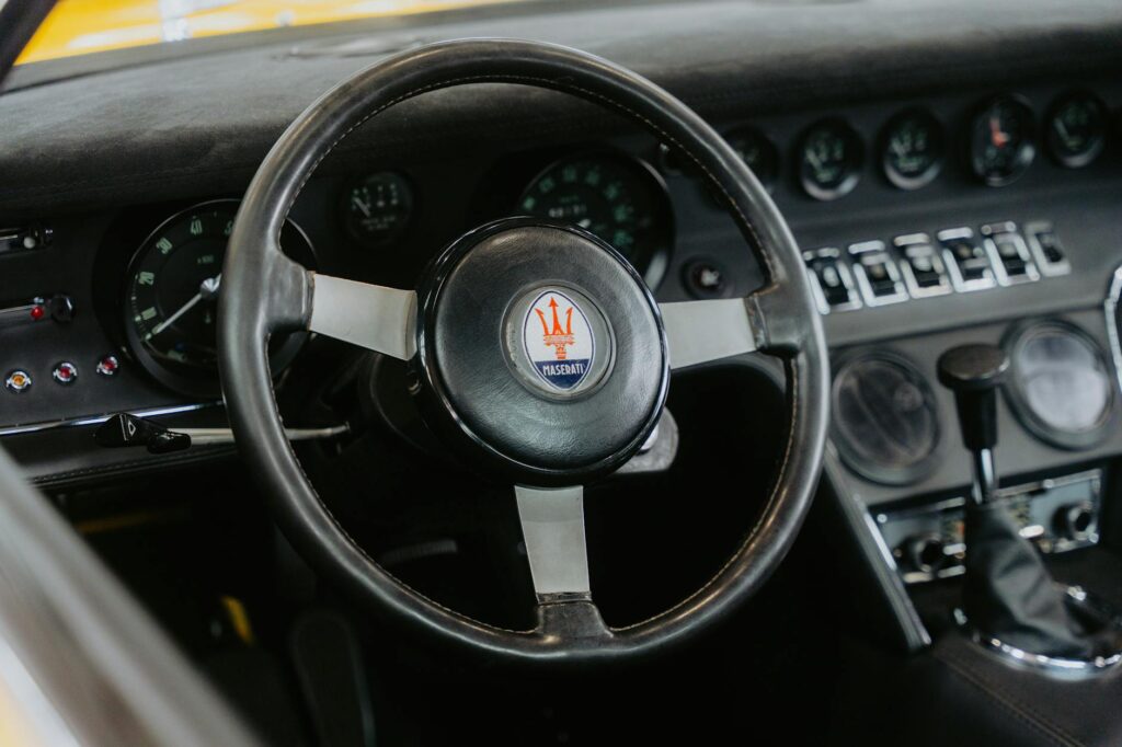 Gros plan d'un volant et d'un tableau de bord Maserati classiques offrant une vue intérieure d'une voiture d'époque.