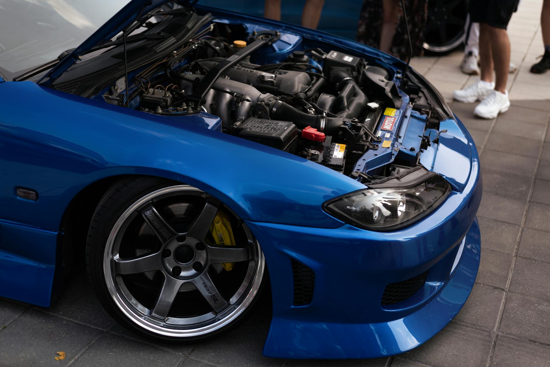 Vue détaillée d'une voiture de sport bleue avec son capot ouvert, mettant en valeur le moteur.