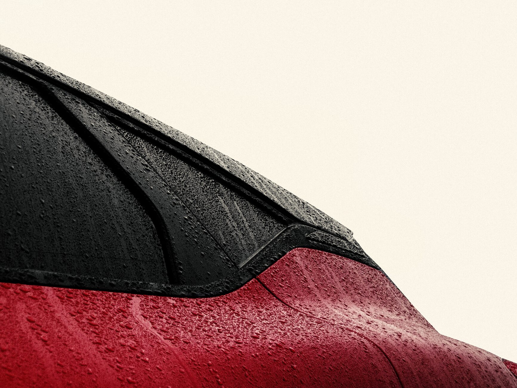 Gros plan sur la vitre d'une voiture rouge avec des gouttelettes de pluie, mettant en valeur un design élégant et une surface réfléchissante.
