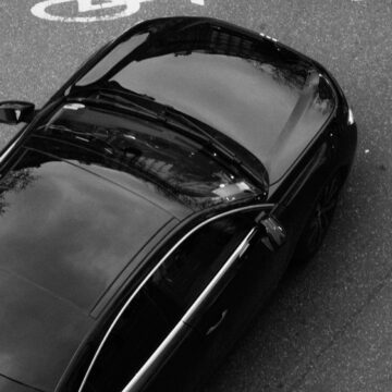Image monochrome d'une voiture noire vue d'en haut, mettant en valeur son design élégant et sa surface réfléchissante.