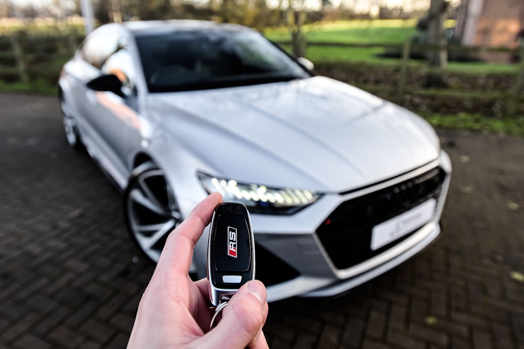 une personne tenant une clé de voiture devant une voiture argentée